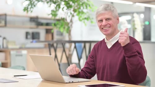 Smiling Man at Laptop Gives Thumbs Up