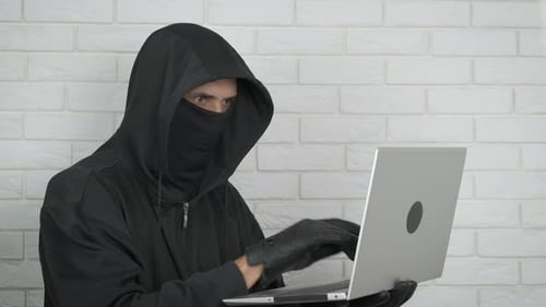 Hooded Person Opens and Types on Laptop