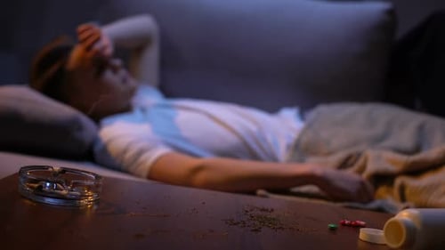 Étudiant toxicomane endormi, cigarette qui couve dans un cendrier, risque d'incendie