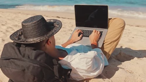 Close Up Behind Shoulder Shot of Young Professional Freelancer or Tourist, Lay on Beach Barefoot