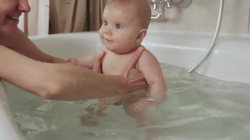 Loving Adult Bathing Adorable Baby in Bathtub