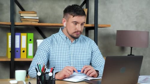 Man Working At Desk with Laptop and Notebook