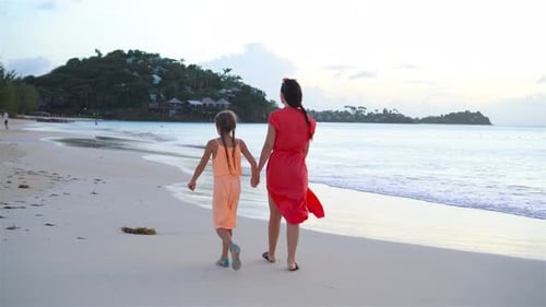 Woman and Girl Walking on Beach at Sunset