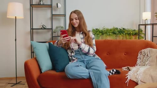 Young Woman Using Smartphone Relaxing on Couch at Home