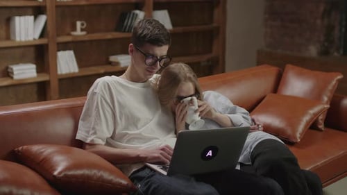 Young Couple Relaxing on Couch with Laptop