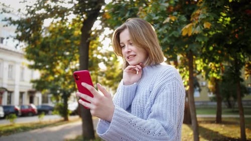 Happy girl having fun, making selfie photos on smartphone outdoor. Student using mobile application.