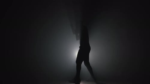 Silhouette eines jungen Boxers, der Boxschläge übt, Training im Dark Smoky Studio. Training in