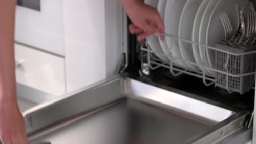 Adult Loading White Plates Into Dishwasher