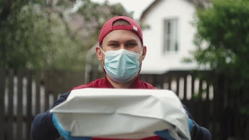 Masked Delivery Person Holding Package Outside Home