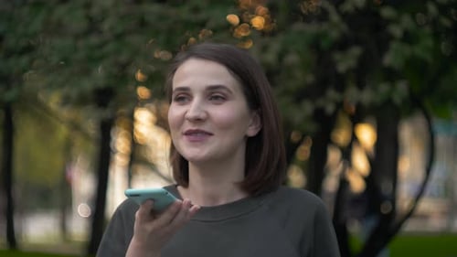 Happy Girl Using a Smart Phone Voice Recognition Audio Message Function on Line Walking on a Street