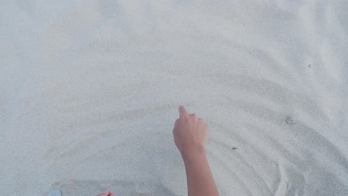 Frau zeichnet Herz auf Sand. Symbol der Liebe und Romantik am Strand.