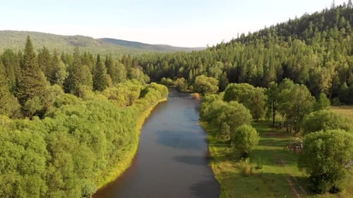 Luftflug der Drohne über Gebirgsfluss, Feld, Wald und Pfad.