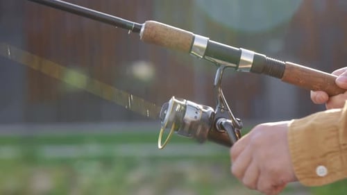 Die Hände des Fischers rollen die Angelrute ein oder haben einen Fisch am Haken gefangen und rollen in der