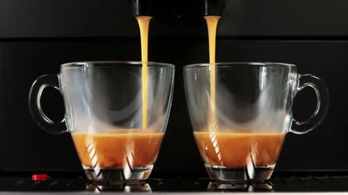 Gebrühter Kaffee wird aus der Kaffeemaschine in Glasbecher gegossen