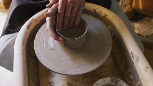 Vue rapprochée d'un potier créant de la poterie sur une roue de potier dans un atelier de poterie