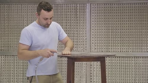 Trabajador que utiliza aerógrafo para aplicar retardante de llama a los detalles de madera asegurando la protección contra incendios
