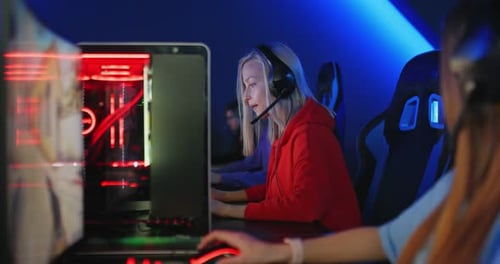 Beautiful Young Women Are Sitting at Computers with Headphones in a Computer Club, Team Game Online