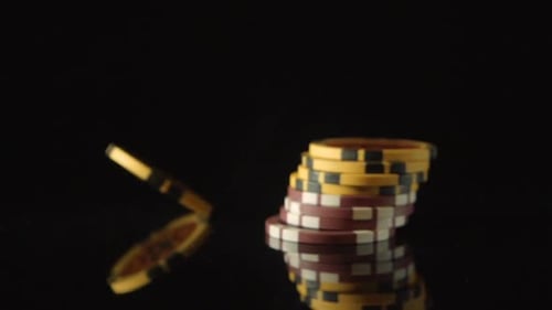 A playing chips falls on a black desk