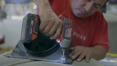 Worker drilling a hole into oven in workshop