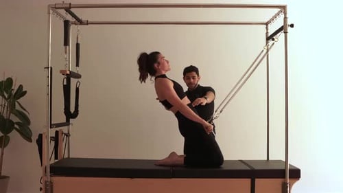 Woman Doing Pilates Reformer Exercise with Instructor