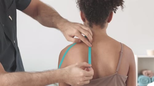 Applying Therapeutic Tape to Patient's Shoulder