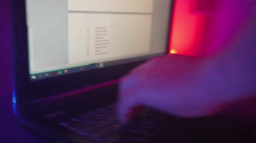 Hands Typing on Laptop Keyboard in Colorful Lighting