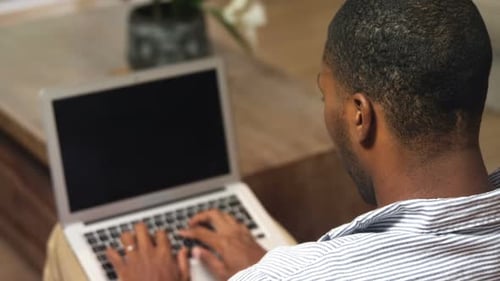 Man Using Laptop Indoors Smiling at Camera