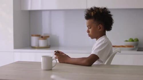 Boy Using Mobile Device in Bright Modern Kitchen