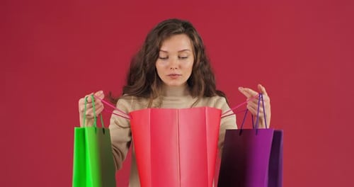 Woman Looks Into Shopping Bags With Happy Surprise