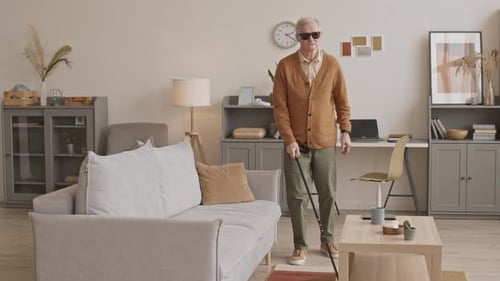 Blinder älterer Mann mit Stock zu Hause