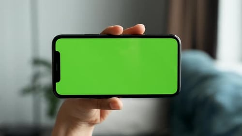 Close-Up Of A Woman's Hand Holding Horizontally A Smartphone with A Green Screen