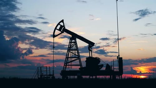 Silhouette Working Oil Pump in Deserted District at Sunset