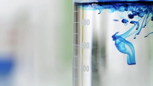 Close view of blue liquid mixing with clear liquid