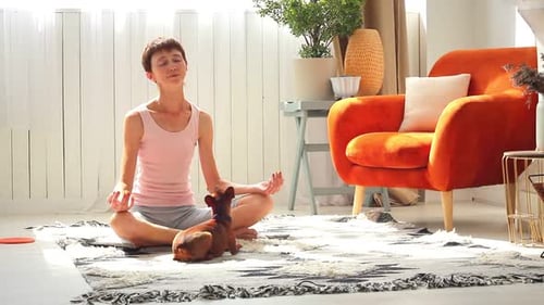 Woman Meditating at Home With Her Dog