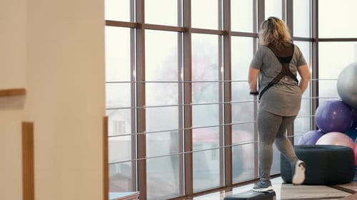 Woman with Excess Weight Training in Gym with Stepper