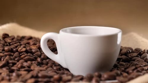 Heiße dampfende Tasse Kaffee auf Jutehintergrund und Kaffeebohnen