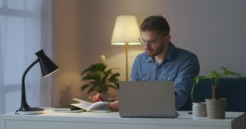 Young Man Studying at Desk with Laptop