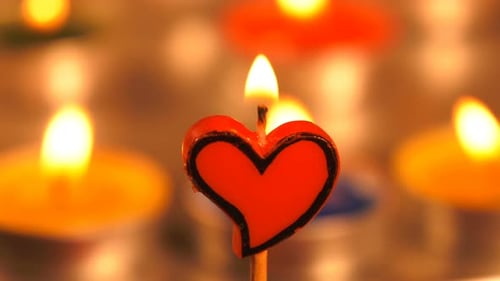 Heart Shaped Candle Burning Among Other Candles