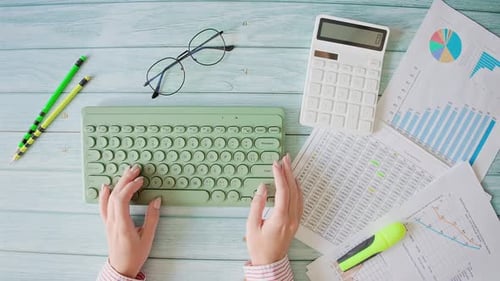 Woman Typing and Highlighting Charts in an Office