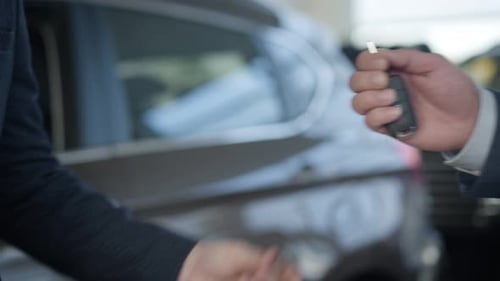 Close-up of Unrecognizable Caucasian Men in Business Suits Passing Car Keys and Shaking Hands