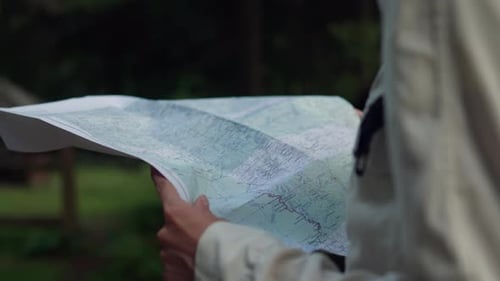 Woman With Backpack Navigates Using Map in Forest