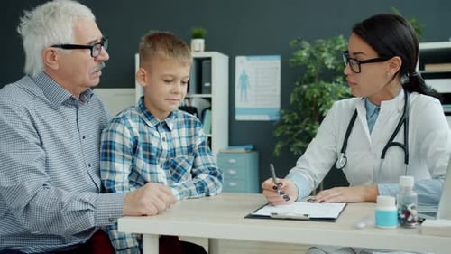 Young Woman Medic Talking To Elderly Man and Child During Appointment in Clinic