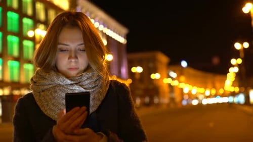 Woman Uses Mobile Phone at Night in City