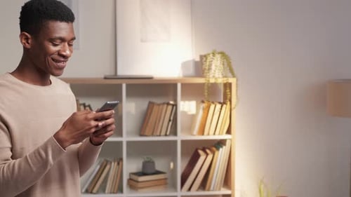Young Adult Smiling While Using Mobile Phone Indoors