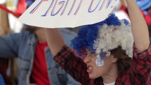 Female Fan with Banner Cheering at Football Game