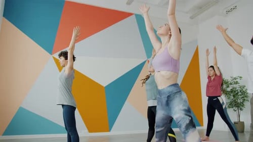 Girls and Guy Bending Forward During Yoga Practice in Spacious Gym Training Together