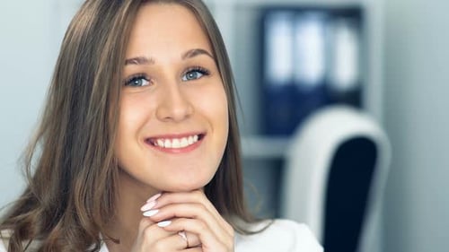 Cheerful Businesswoman Sitting at the Table in Office and Looking at Camera