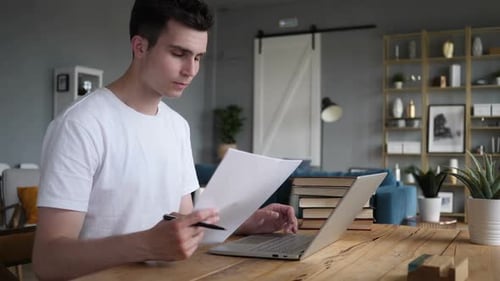 Young Adult Man Working at Home with Laptop