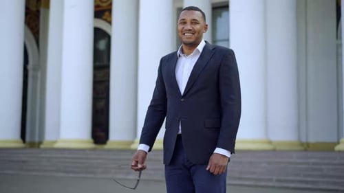 Smiling Businessman in Suit Stands Near Columns