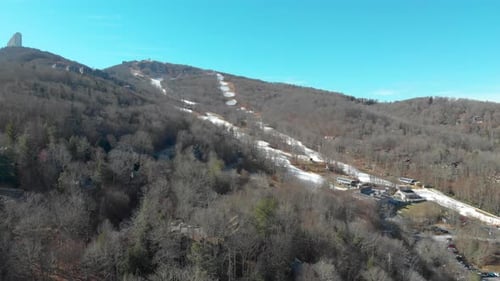 A drone shot of a mountain in winter and the ski slopes.